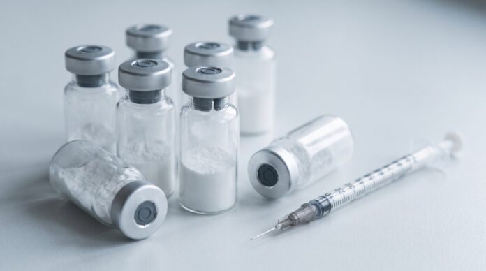 Vials of white lyophilized injectable peptide powder with a syringe, representing unauthorized peptide drugs sold online in Canada