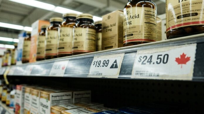 Grocery shelf label showing a triangle T tariff symbol beside a maple leaf Canadian product tag, supplement bottles above