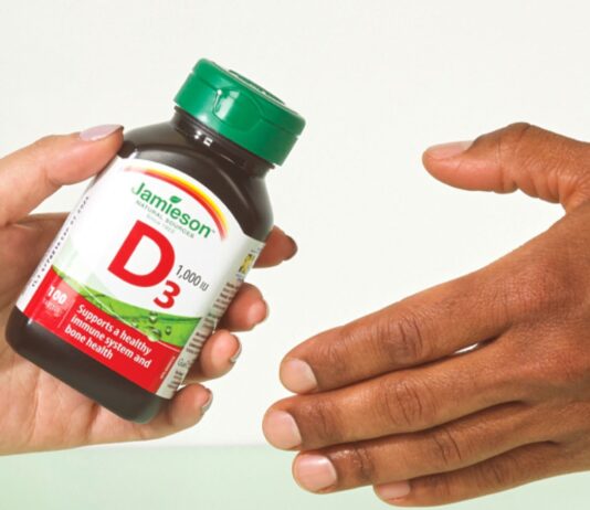 Jamieson Shareholders Approve Kirin Takeover, With 29.5% Opposed Jamieson Wellness Kirin shareholder vote: a Jamieson vitamin D3 bottle handed from one person to another, illustrating the sale of the company to Kirin Holdings